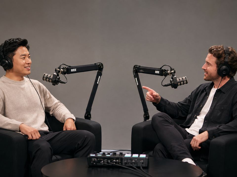 Two people talking across a table of microphones